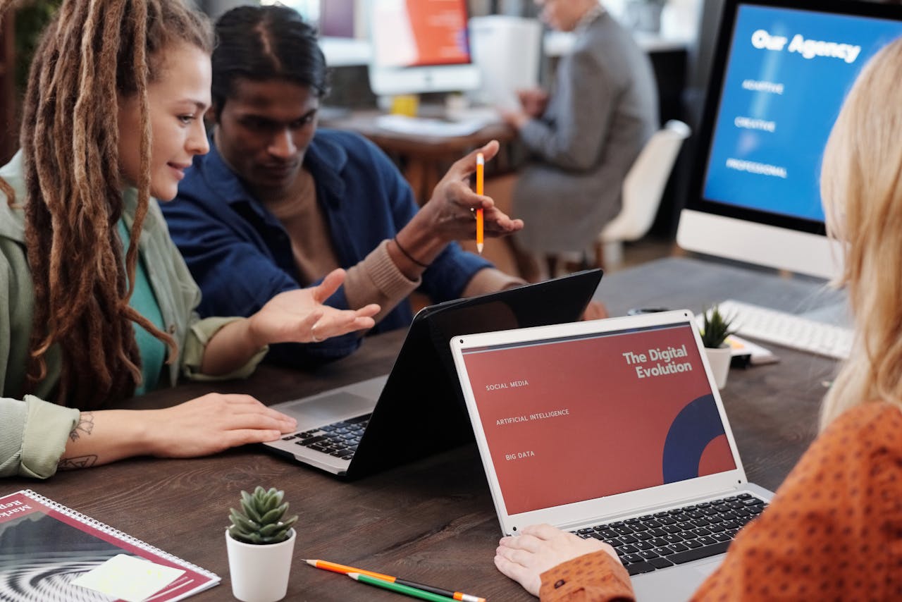 Our Services Diverse team collaborating with laptops in a modern office setting, discussing digital evolution.