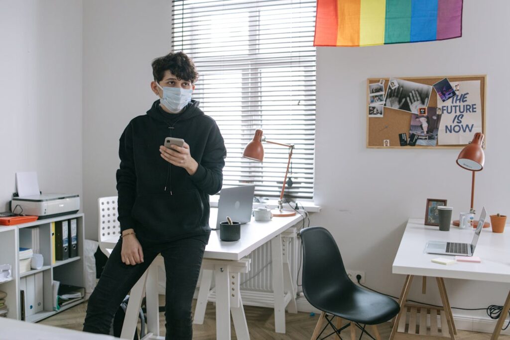 Home Young man in a modern office wearing a mask, symbolizing the new normal and workplace safety.